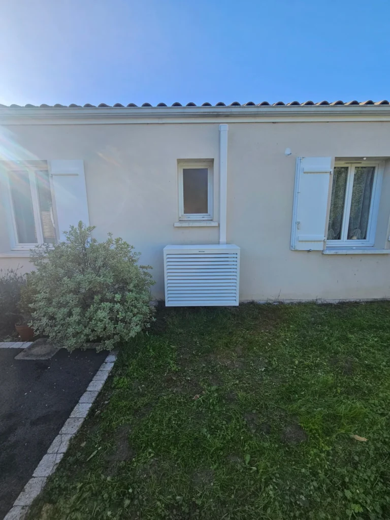 Façade d'une maison de plain-pied avec le groupe extérieur de climatisation sous son cache à lames, Benon