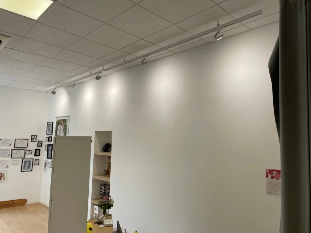 Rail d'éclairage blanc avec cinq projecteurs LED suspendu sous le faux plafond d'une boutique, La Rochelle