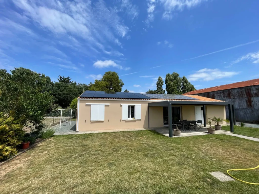 Maison de plain-pied avec douze panneaux solaires en deux lignes sur le toit, vue du jardin, La Laigne