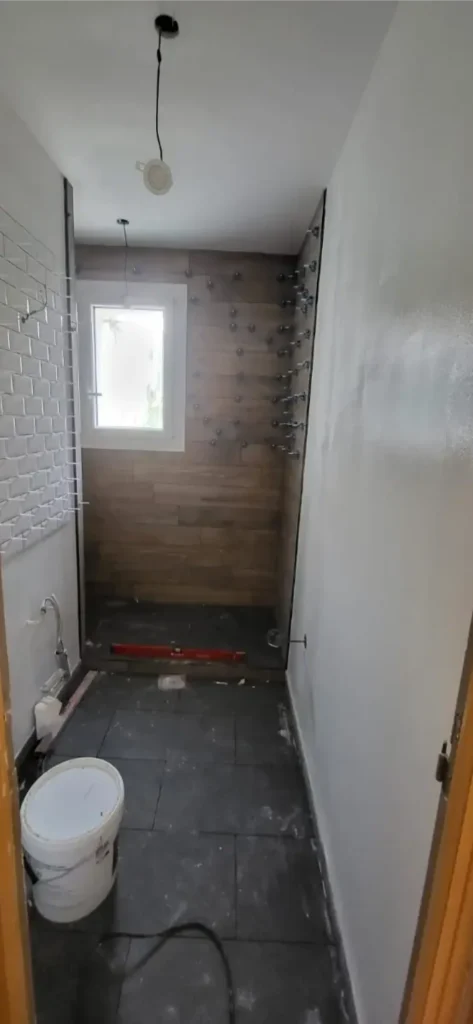 Pose du carrelage effet bois dans la douche, croisillons en place